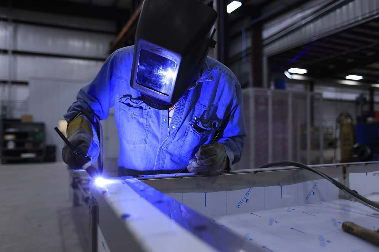 A welder constructing the components of a DIY steel building kit