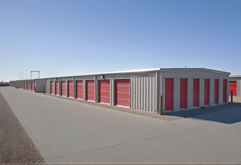 Durable steel storage units with red roll-up doors on a gravel lot, designed for storage businesses.