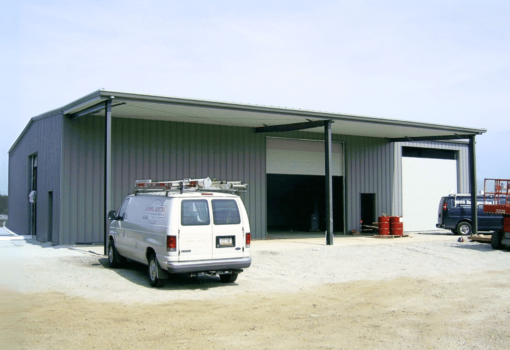 Multi-bay steel carport with metal siding, commercial vans, and wide open bays